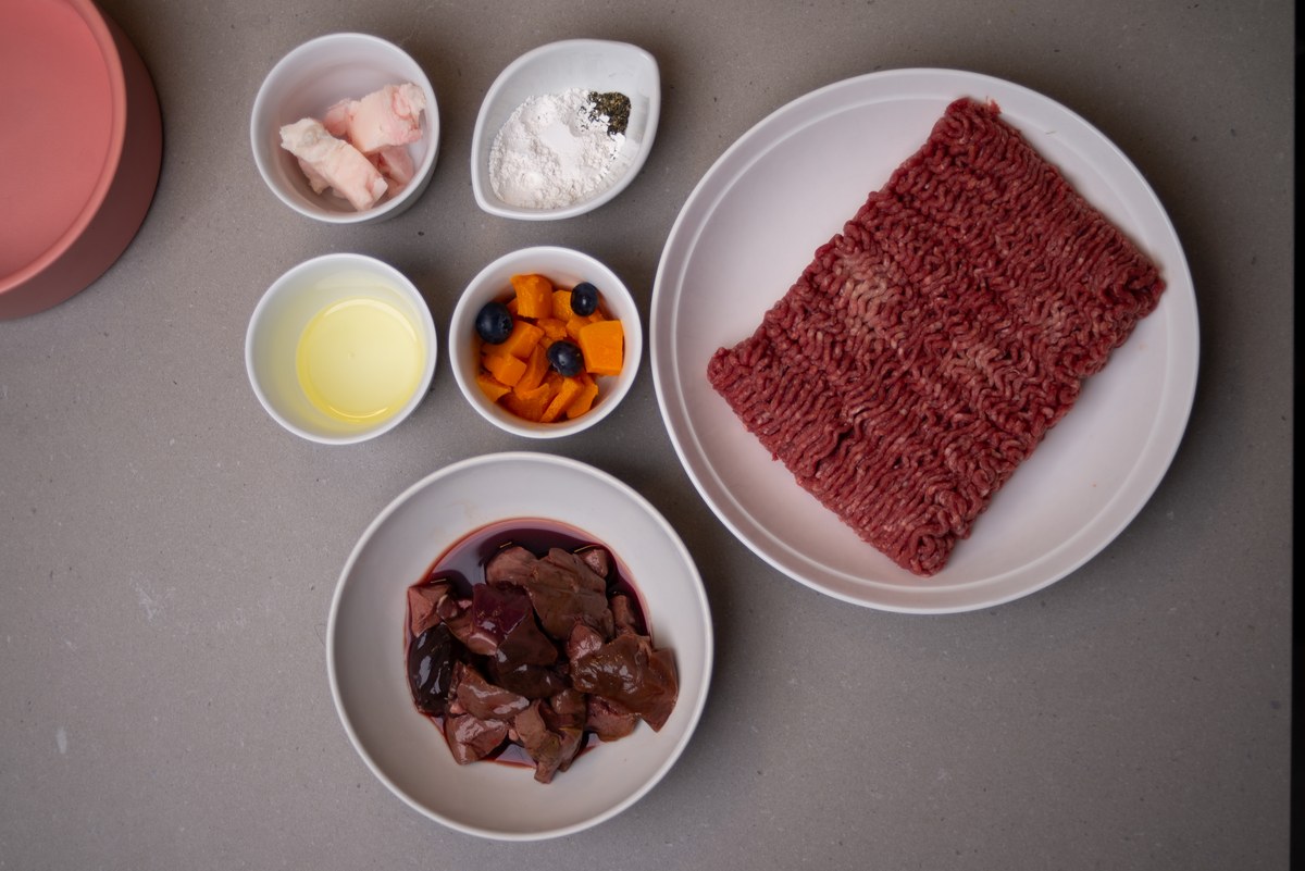 Ingredients for a single protein elimination diet bowl laid out in white dishes: beef mince, liver, fat, egg white, pumpkin and blueberries